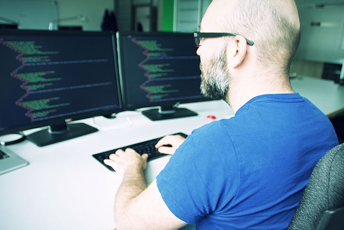 Neos IT Services, working environment, employee is coding in front of a screen